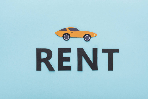 top view of paper cut sports car and black rent lettering on blue background - Photo, Image