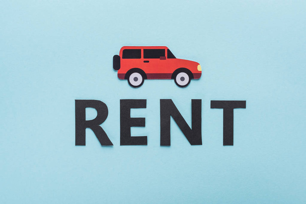 top view of paper cut car and black rent lettering on blue background - Photo, Image