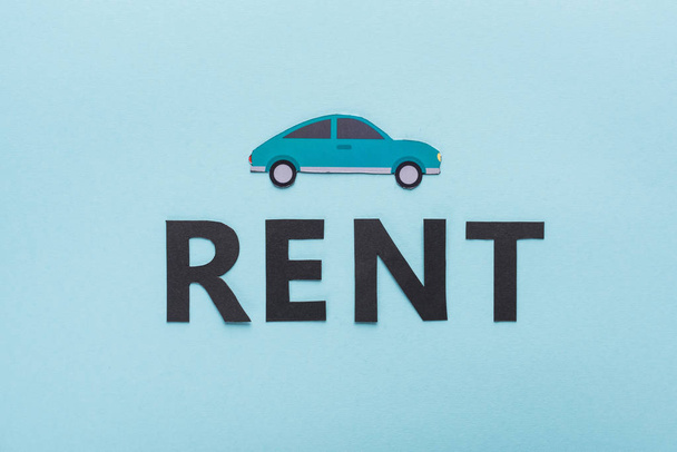 top view of paper cut car and black rent lettering on blue background - Foto, immagini