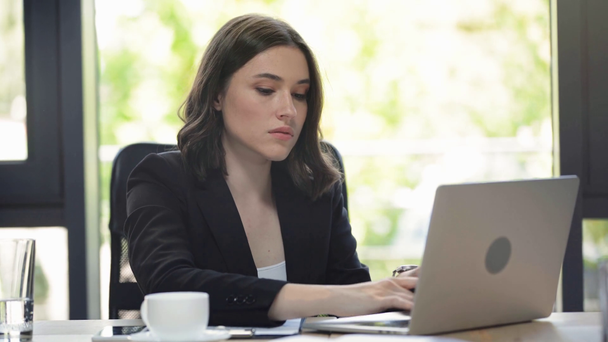 concentrated businesswoman writing in notebook and using laptop - Footage, Video