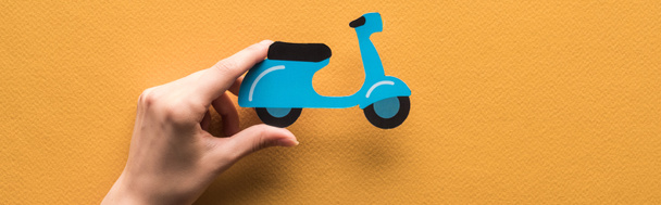 cropped view of woman holding paper cut scooter on orange background, panoramic shot - Fotoğraf, Görsel