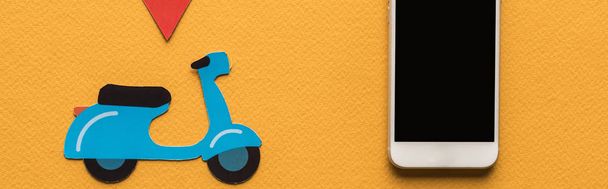 vista superior de scooter de corte de papel, marca de ubicación cerca de teléfono inteligente con pantalla en blanco sobre fondo naranja, plano panorámico
 - Foto, imagen