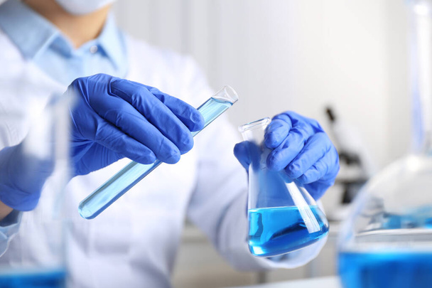 Doctor pouring blue liquid into flask, closeup. Laboratory analysis - Valokuva, kuva