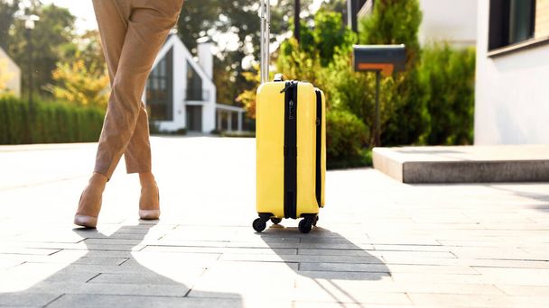 Young businesswoman with yellow suitcase outdoors. Moving day - Foto, imagen