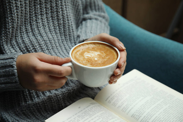 Mujer con taza de libro de lectura de café en casa, primer plano
 - Foto, Imagen