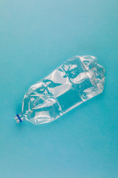 Gekromde plastic flessen op een blauwe achtergrond. Kunststof afval. - Foto, afbeelding