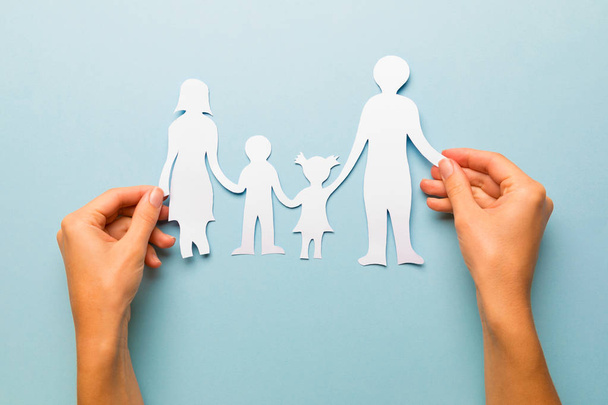 Бумажная семья в руке изолированы на синем фоне
 - Фото, изображение