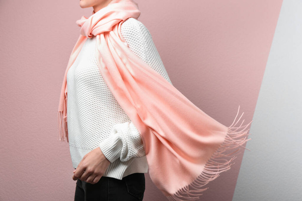 Woman wearing warm scarf on color background, closeup. Autumn clothes - 写真・画像