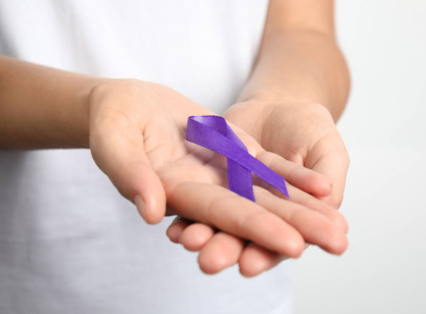 Woman holding purple ribbon on white background, closeup. Domestic violence awareness - Foto, imagen