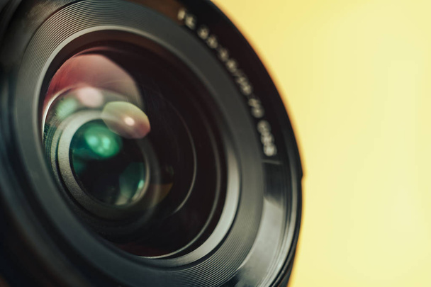 Hermosa lente de cámara con luz amarilla y rosa de vidrio sobre un fondo negro
. - Foto, Imagen