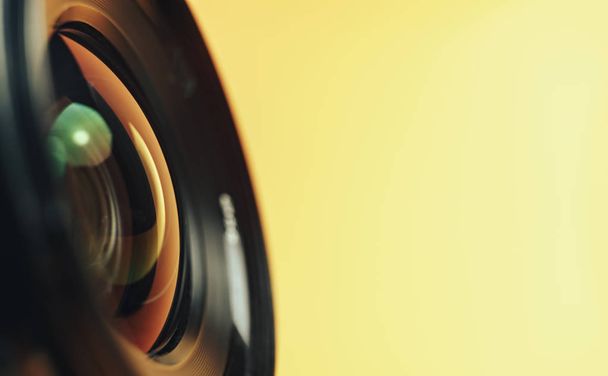Beautiful camera lens with yellow and pink light of glass on a black background. - Photo, Image