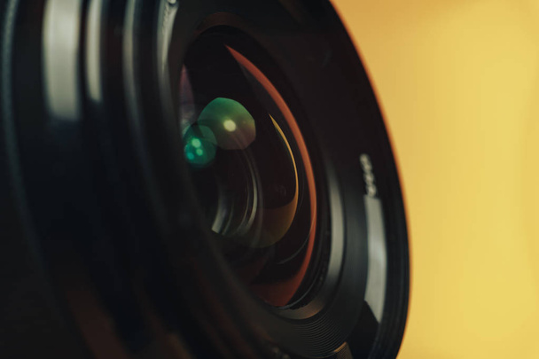 Κοντινό πλάνο όμορφο μαύρο φακό κάμερα σε ένα κίτρινο φόντο. Μακροσκοπική προβολή.. - Φωτογραφία, εικόνα
