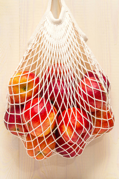 Red apples in a mesh cotton bag - 写真・画像