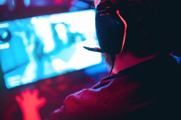 Sfondo sfocato giocatore professionista giocare tornei giochi online computer con cuffie, rosso e blu - Foto, immagini