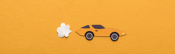 horní pohled na papír řezané sportovní auto s výfukovým plynem na oranžovém pozadí, panoramatický záběr - Fotografie, Obrázek