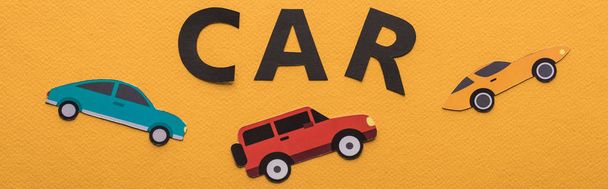 top view of paper cut vehicles and black car lettering on orange background, panoramic shot - Photo, Image