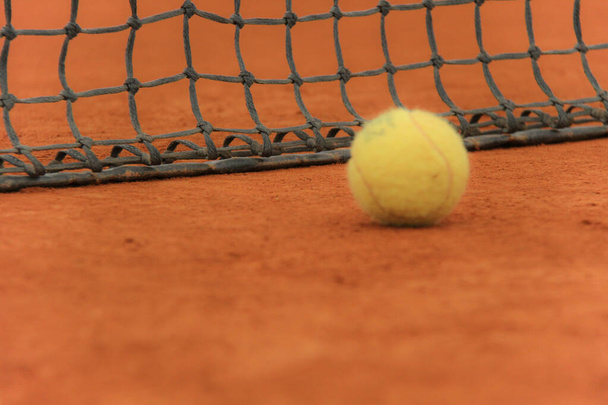 Tennis balls on red court with gray net - Photo, Image