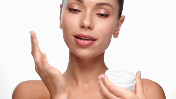 kobieta uśmiechająca się i stosująca krem kosmetyczny izolowany na biało - Materiał filmowy, wideo