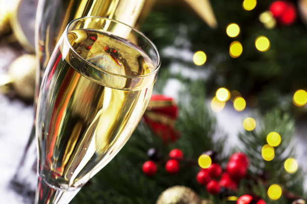 Dos copas de champán y decoración navideña sobre fondo bokeh azul nieve dorada. Feliz Año Nuevo. Enfoque selectivo y pequeña profundidad de campo - Foto, imagen