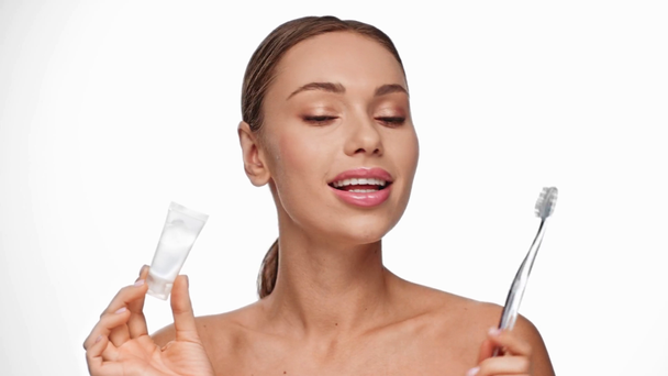 žena držící zubní kartáček a zubní pastu izolované na bílém - Záběry, video