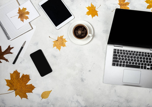 Робочий простір з осіннім жовтим листям, ноутбуком, планшетом, смартфоном, блокнотом і чашкою кави. Вид зверху на осіннє робоче місце фрілансера
. - Фото, зображення