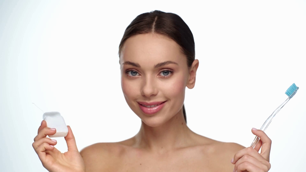 žena držící zubní kartáček a zubní nit izolované na bílém - Záběry, video