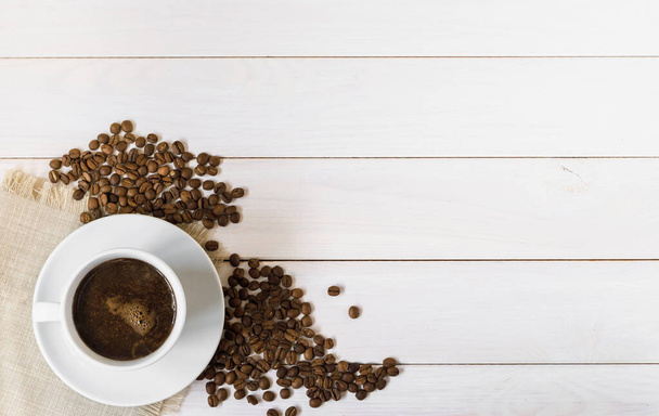 šálek kávy a kávová zrna na dřevěném stole - Fotografie, Obrázek