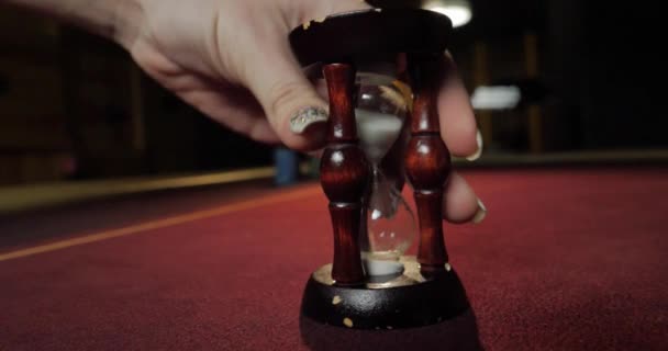 Dealer puts an hourglass on the poker table. Close-up of woman's hand. - Footage, Video