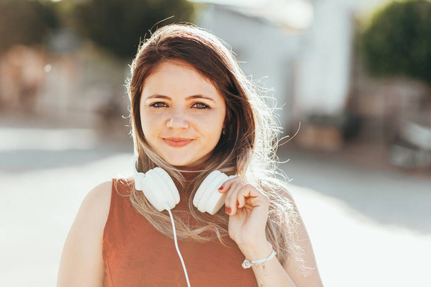 Portret młodej kobiety słuchającej muzyki ze słuchawkami na ulicy na zewnątrz - Zdjęcie, obraz