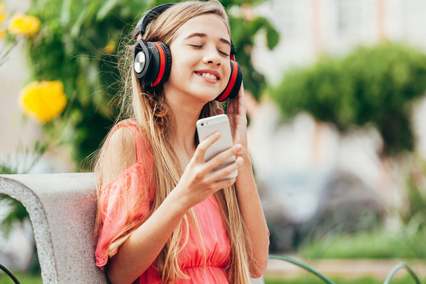 Portrait of teenager girl listening to music outdoors - 写真・画像