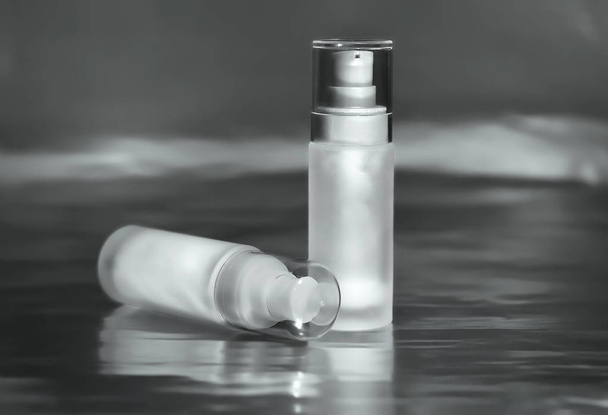 Dos recipientes cosméticos de vidrio para crema facial, suero o gel sobre fondo oscuro
 - Foto, imagen