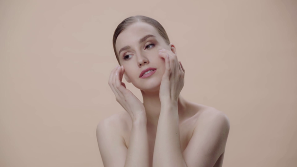 naga kobieta robi masaż twarzy odizolowany na beżowy  - Materiał filmowy, wideo