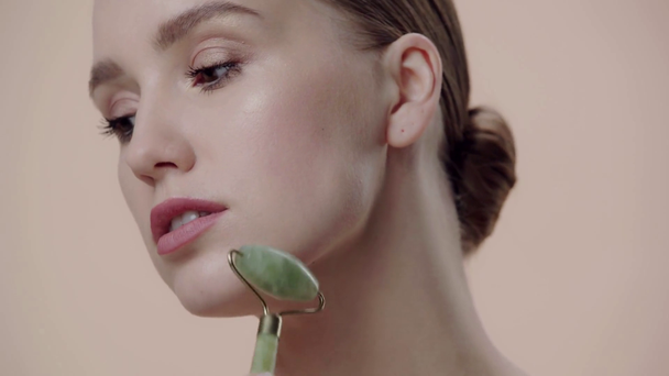 close up de mulher usando rolo de jade isolado no bege
 - Filmagem, Vídeo