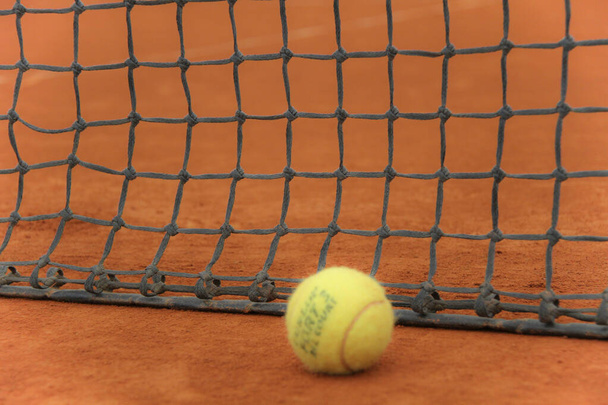 Tennis balls on red court with gray net - Photo, image
