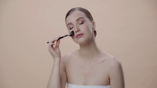 attraktive Frau hält Kosmetikpinsel isoliert auf beige  - Filmmaterial, Video