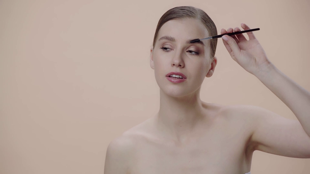 happy woman styling eyebrows isolated on beige  - Footage, Video