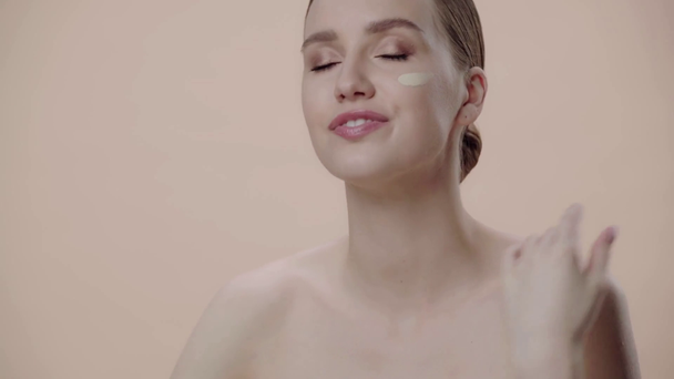 vrouw aanbrengen gezicht stichting geïsoleerd op beige  - Video