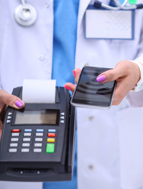Doctor is holding payment terminal in hands. Paying for health care. Doctor - Photo, Image
