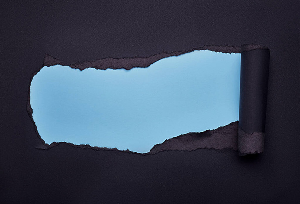 Hole in the black paper. Torn. Wooden background. Abstract background. - Foto, afbeelding