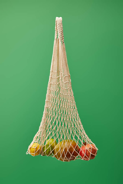 bolsa de hilo con frutas aisladas sobre fondo verde
 - Foto, Imagen