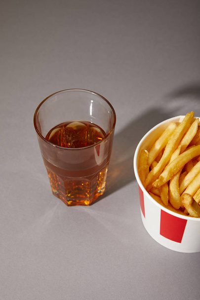 beer in glass near delicious french fries in bucket on grey background - Fotografie, Obrázek