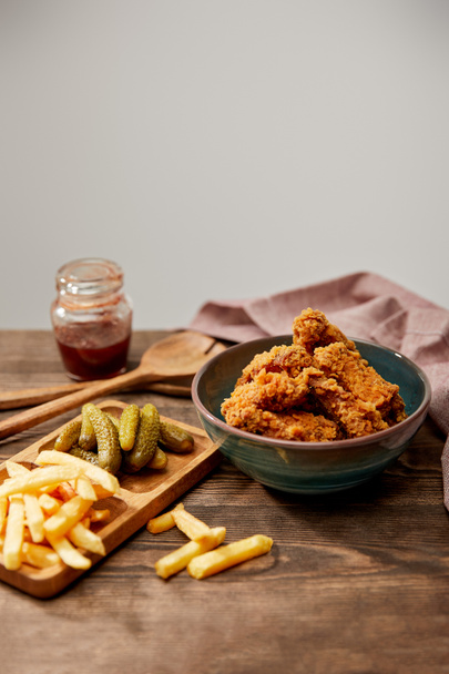 delicious chicken nuggets, french fries and gherkins on wooden table isolated on grey - 写真・画像