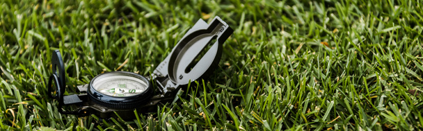 Panoramaaufnahme eines schwarzen Retro-Kompasses auf grünem Gras  - Foto, Bild