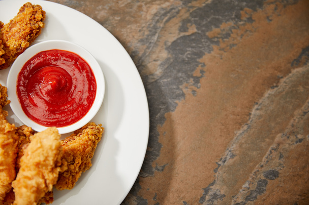 top view of delicious chicken nuggets with ketchup on stone surface - Foto, immagini