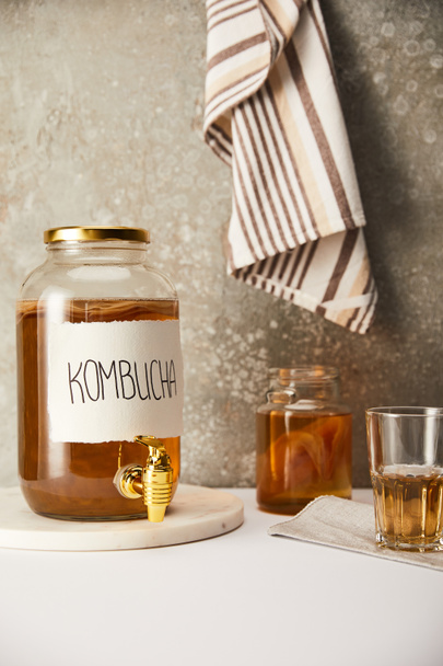 jar with kombucha near glasses on textured grey background with striped napkin - Photo, image