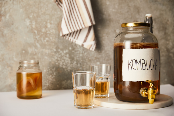 jar with kombucha near glasses on textured grey background with striped napkin - Photo, Image