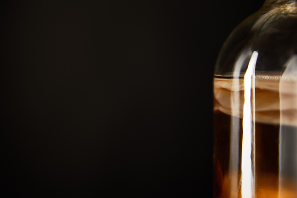 close-up zicht op glazen pot met kombucha geïsoleerd op zwart - Foto, afbeelding