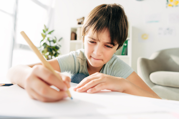 kid with dyslexia drawing with pencil and sitting at table  - Photo, Image