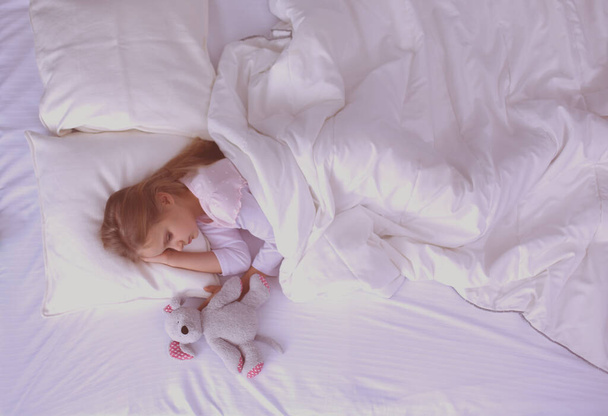 Child little girl sleeps in the bed with a toy teddy bear. - Foto, Imagem