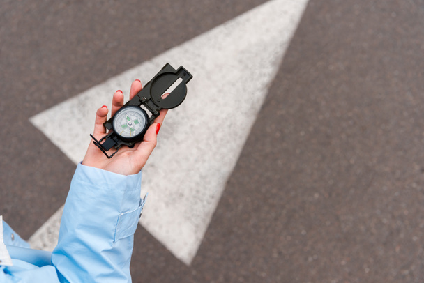 Ausgeschnittene Ansicht einer Frau mit Oldtimer-Kompass in der Nähe der Straße  - Foto, Bild